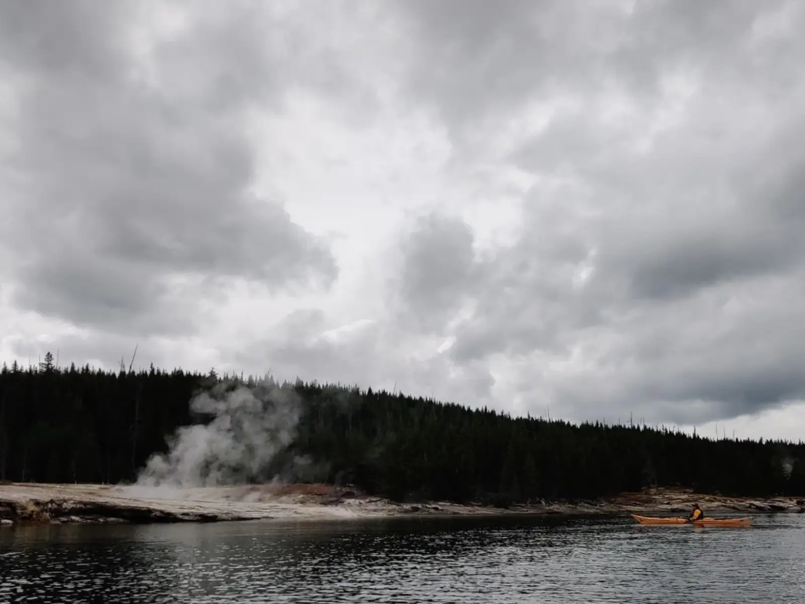 Person in red kayak and calm water surface in Yellowstone National Park.